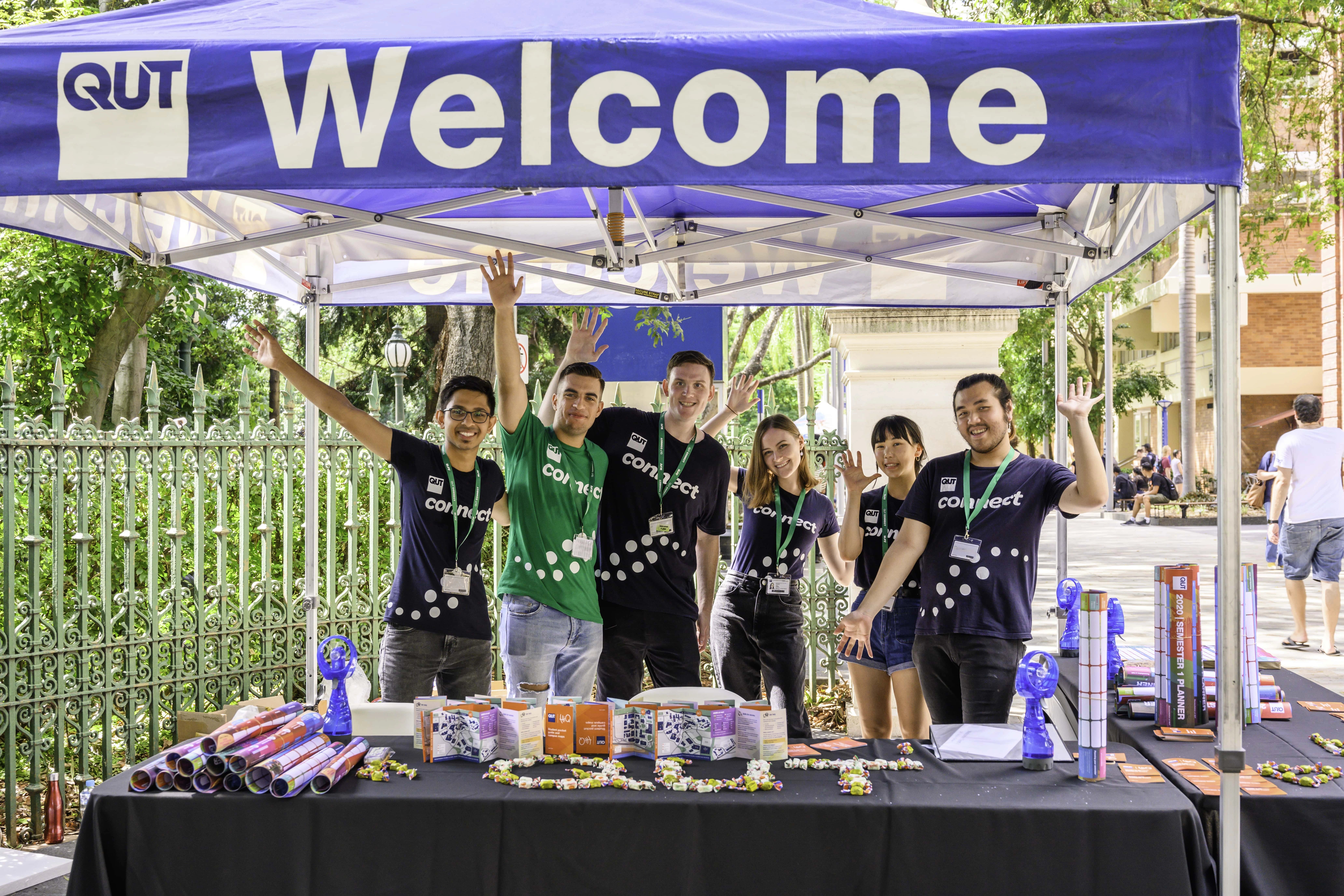 Eine Gruppe Studierende posiert am Willkommen-Stand der Queensland University of Technology