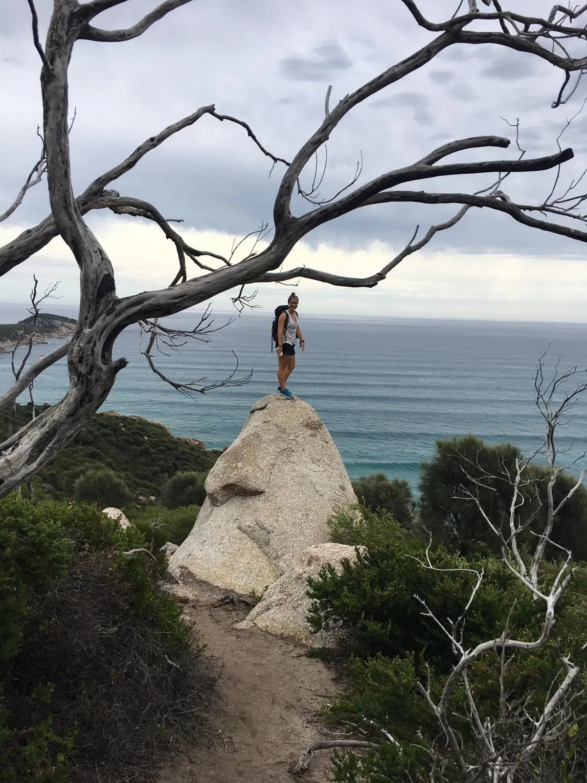 Studentin der Deakin University auf einem Felsen mit Blick auf das Meer.