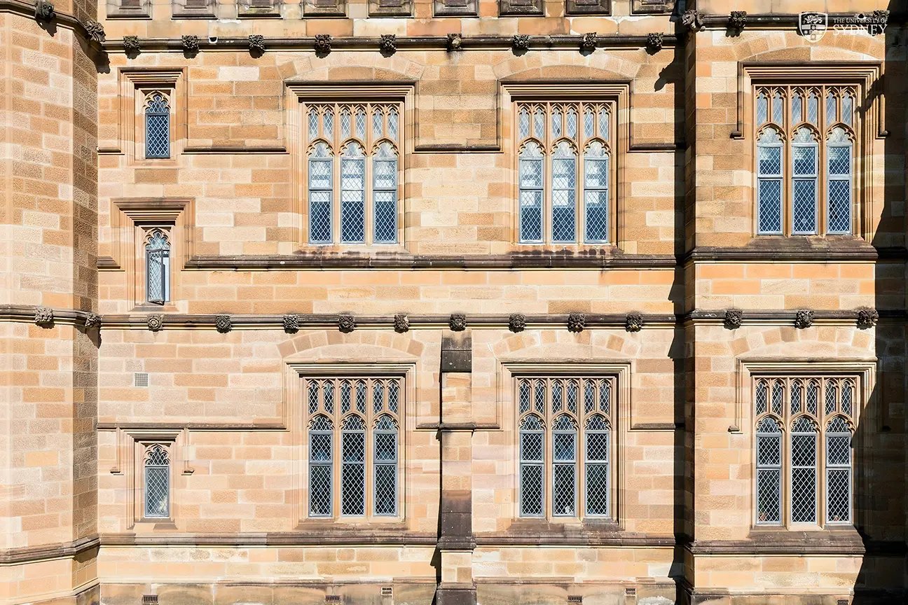 Historische Fassade der University of Sydney aus Sandstein mit verzierten Fenstern und klassischer Architektur.ney_USyd_architecture-bridgequad-sandstone-wall