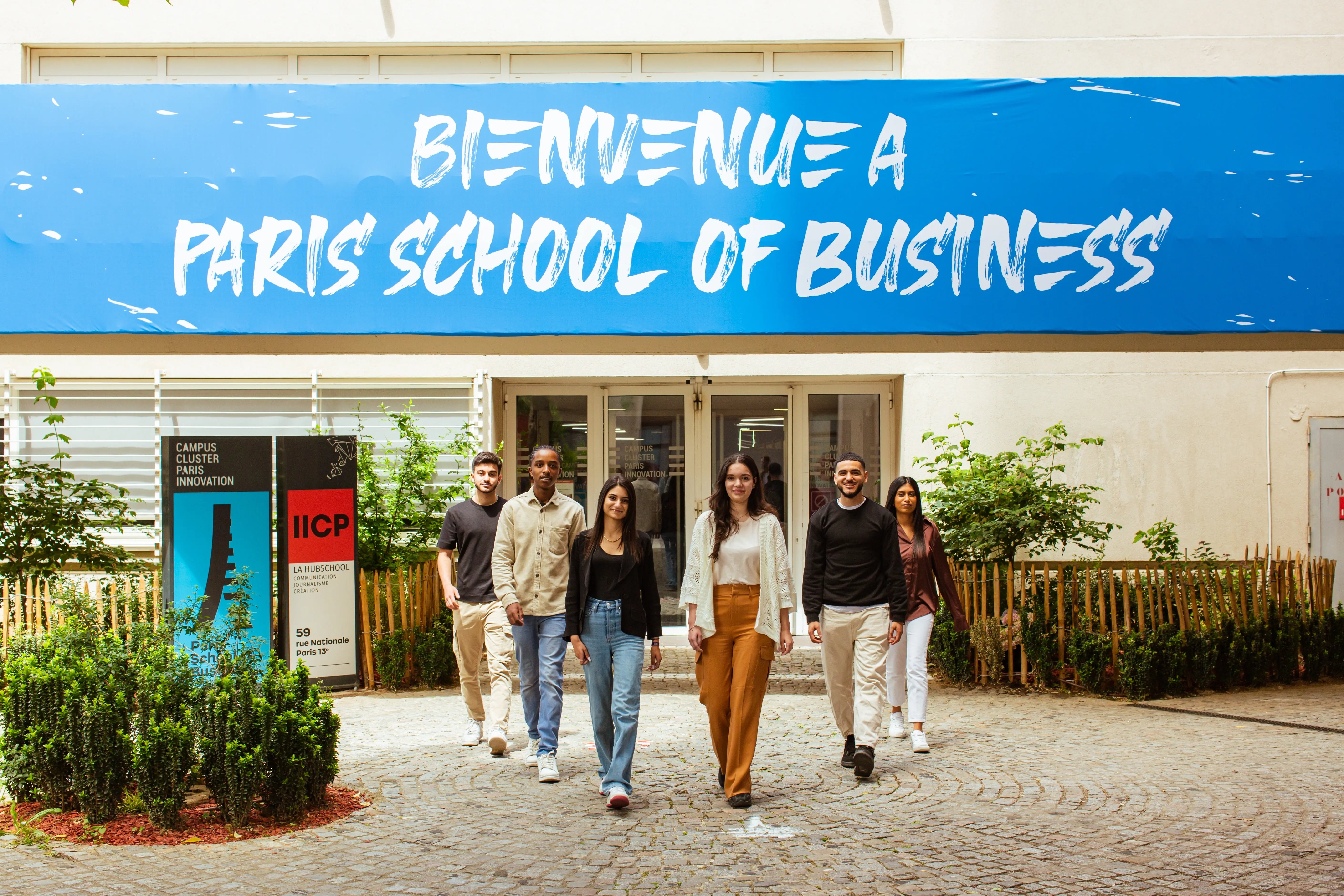 Studierende vor dem Eingang der Paris School of Business mit einem Willkommensschild.