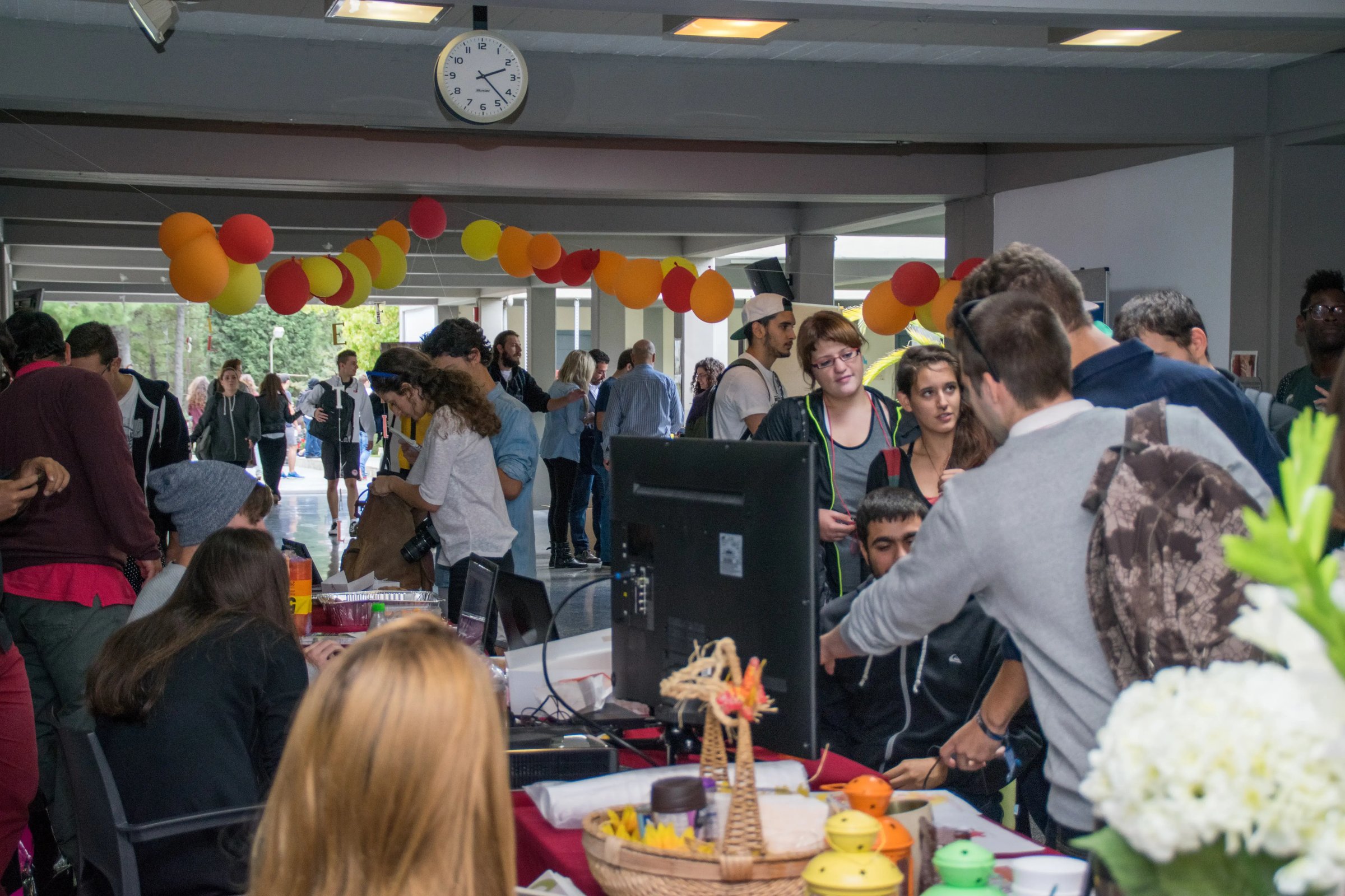 Studierende besuchen einen belebten Infostand mit Deko und Snacks während einer Hochschulveranstaltung.