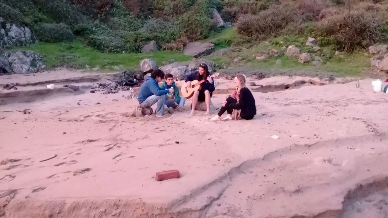 Studierende der Universidad Adolfo Ibanez in Chile sitzen am Strand und genießen die Freizeit mit Musik und Gesprächen.