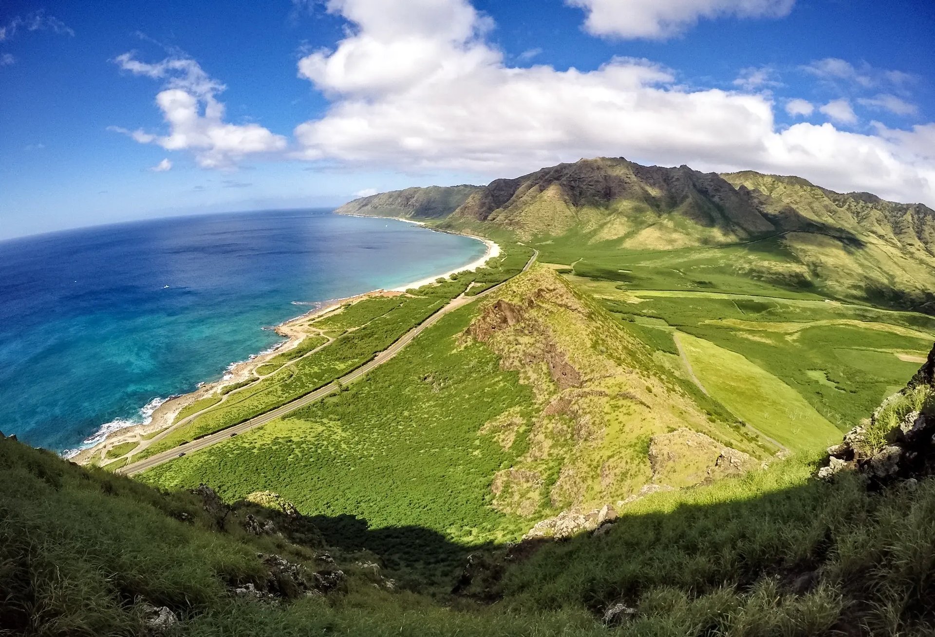 Küstenlandschaft mit grünen Bergen und azurblauem Meer in Hawaii.