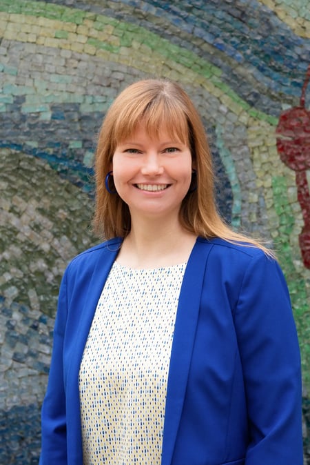 Julia Fischer, Head of University Relations bei IEC Online, steht vor einer bunten Mosaikwand.