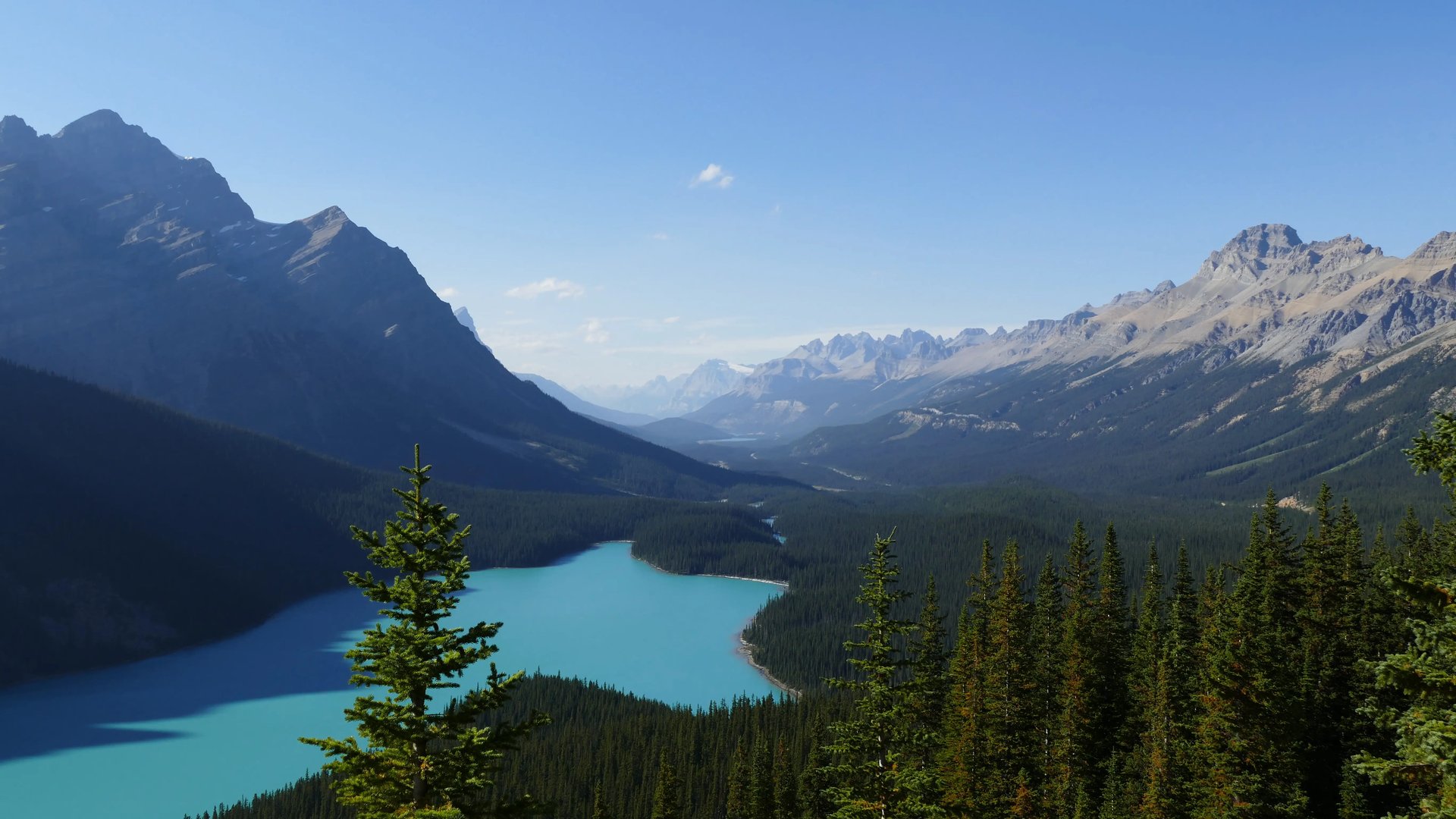 Panoramablick auf die Rocky Mountains mit einem klaren, blauen See im Vordergrund.