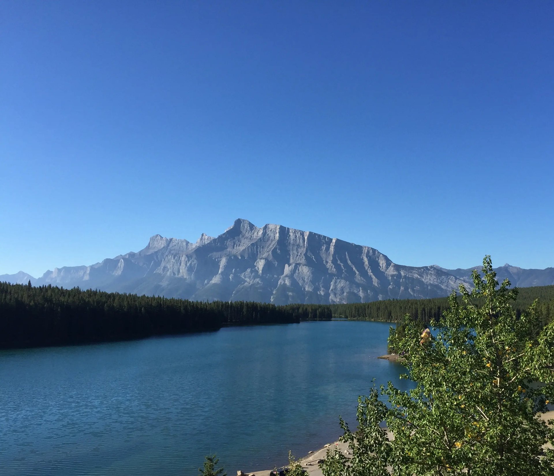 Bergsee in Kanada mit klarem blauen Himmel und beeindruckender Bergkette.
