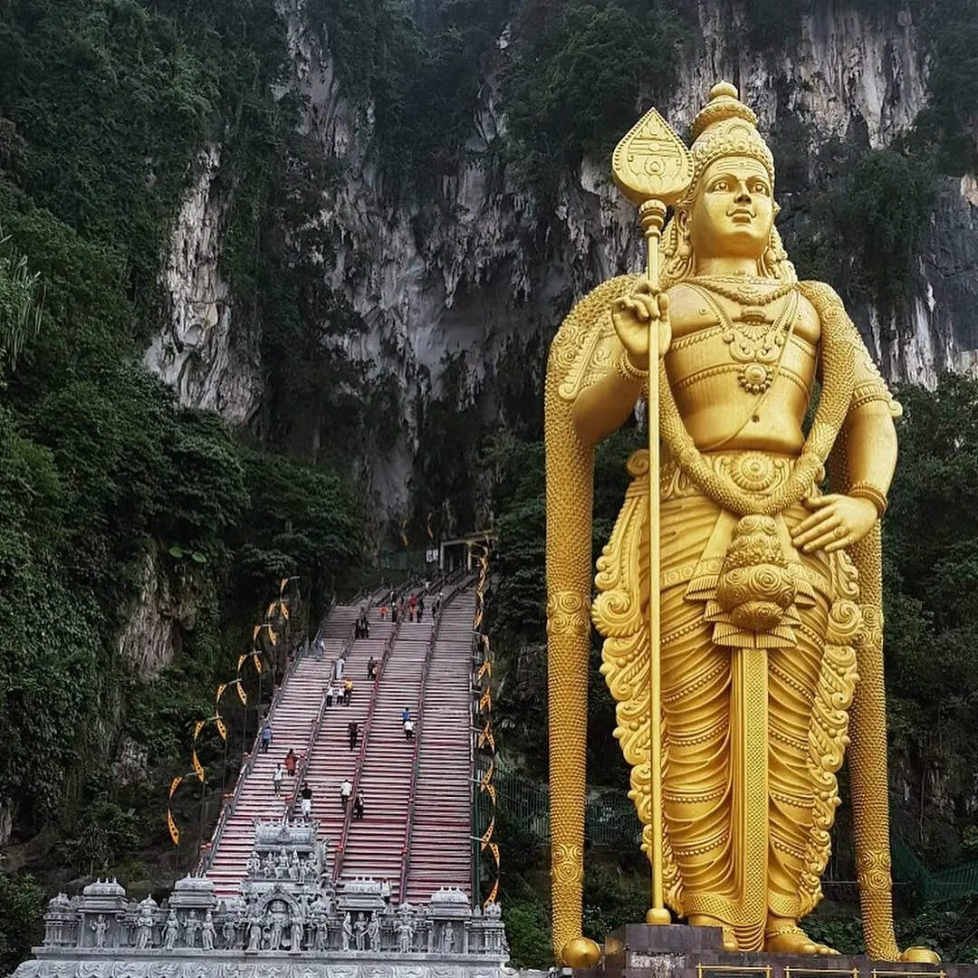Buta Caves und Goldene Statue vor einem Tempel in Malaysia.