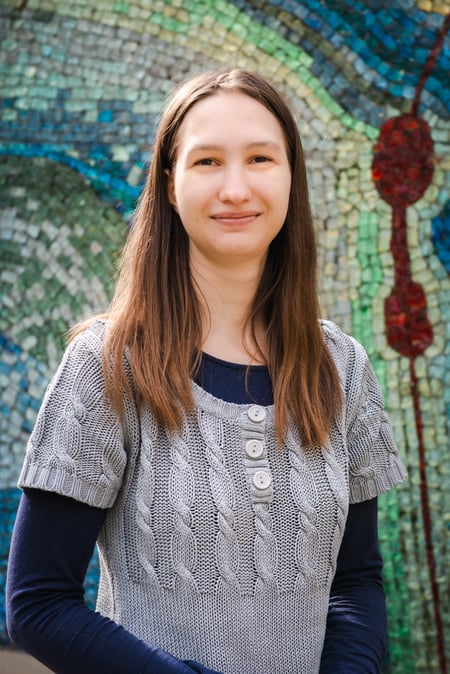 Maria Zasadzki vom IEC Online Team lächelt vor einer bunten Mosaikwand. Maria Zasadzki vom IEC Online Team lächelt vor einer bunten Mosaikwand.