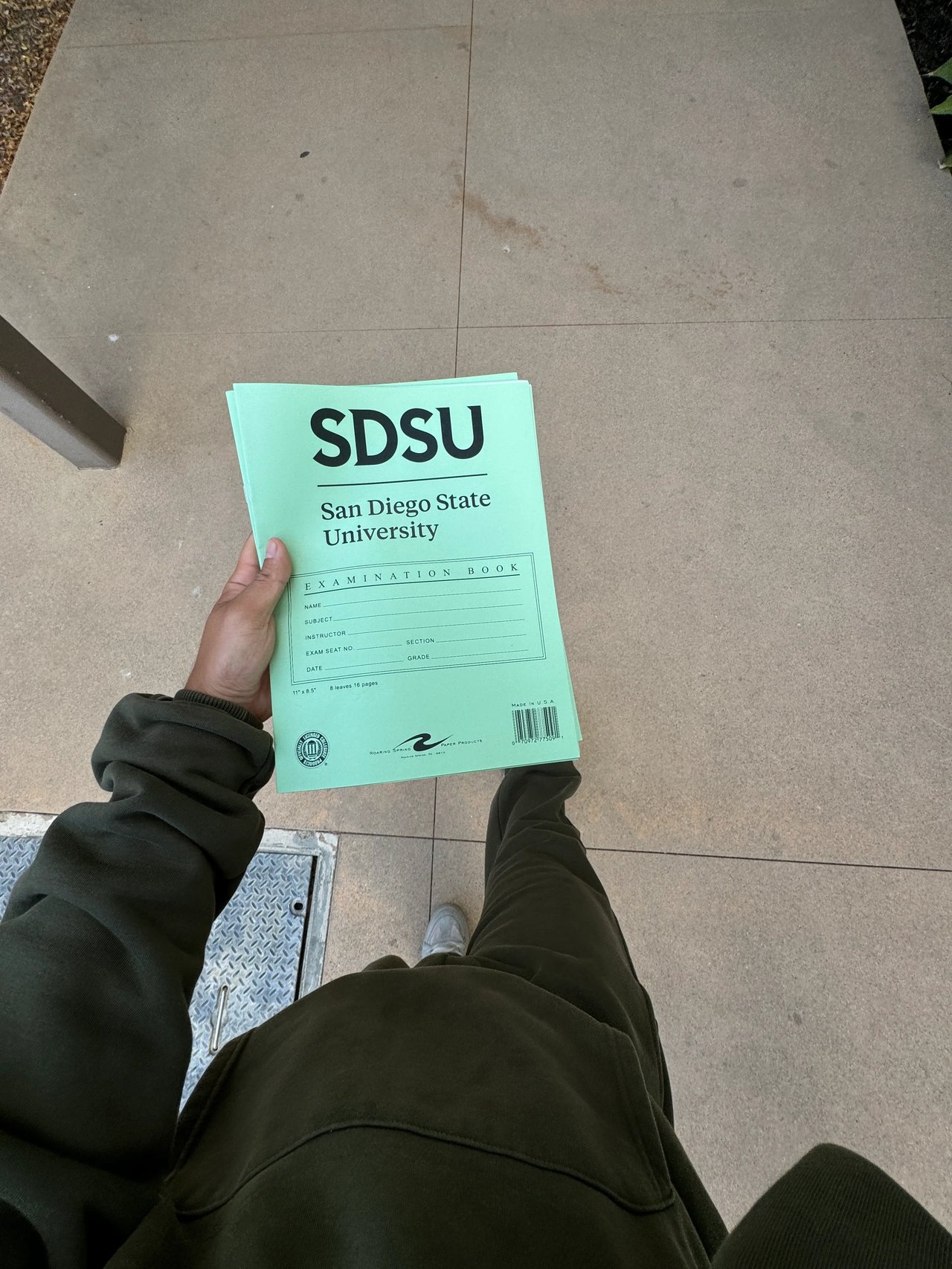 Prüfungsheft der San Diego State University (SDSU) in der Hand eines Studierenden auf dem Campus.