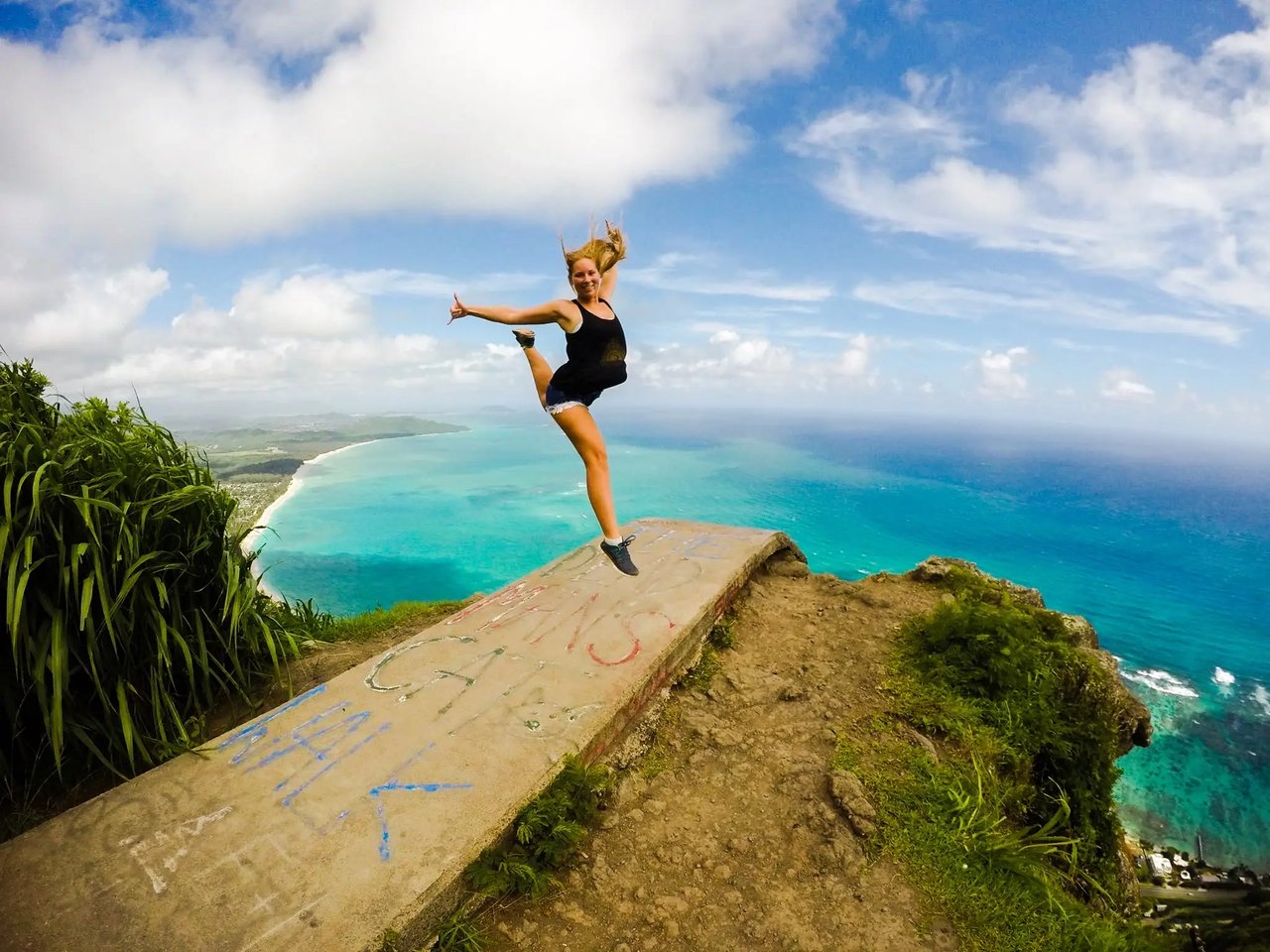 Studentin der Hawaii Pacific University auf einer Klippe mit Ausblick auf das Meer und die Küste von Hawaii.
