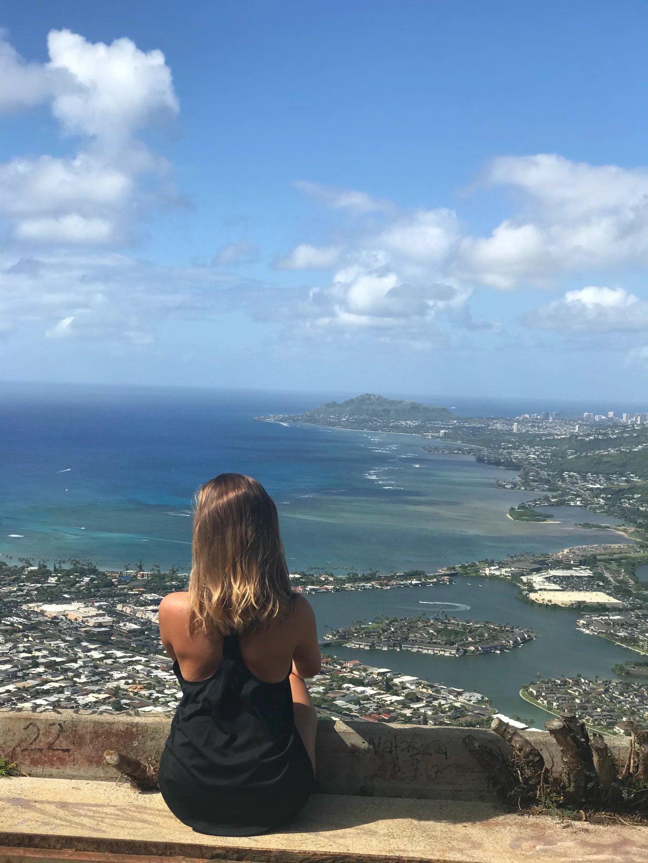 Blick von einem Aussichtspunkt auf Oʻahu mit einer Studentin, die das Panorama des Pazifiks und der Insel bewundert.