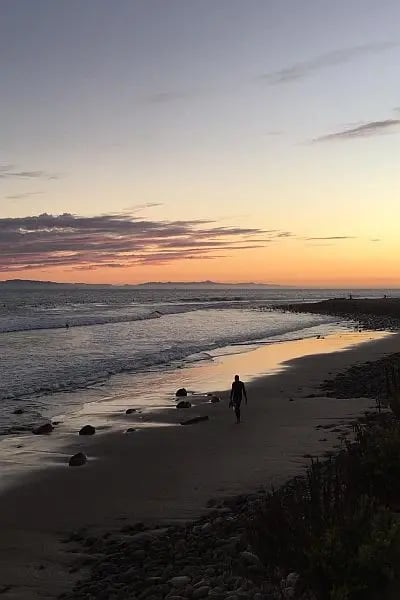 Sonnenuntergang am Strand von Los Angeles, eine Person spaziert entlang der Küste.
