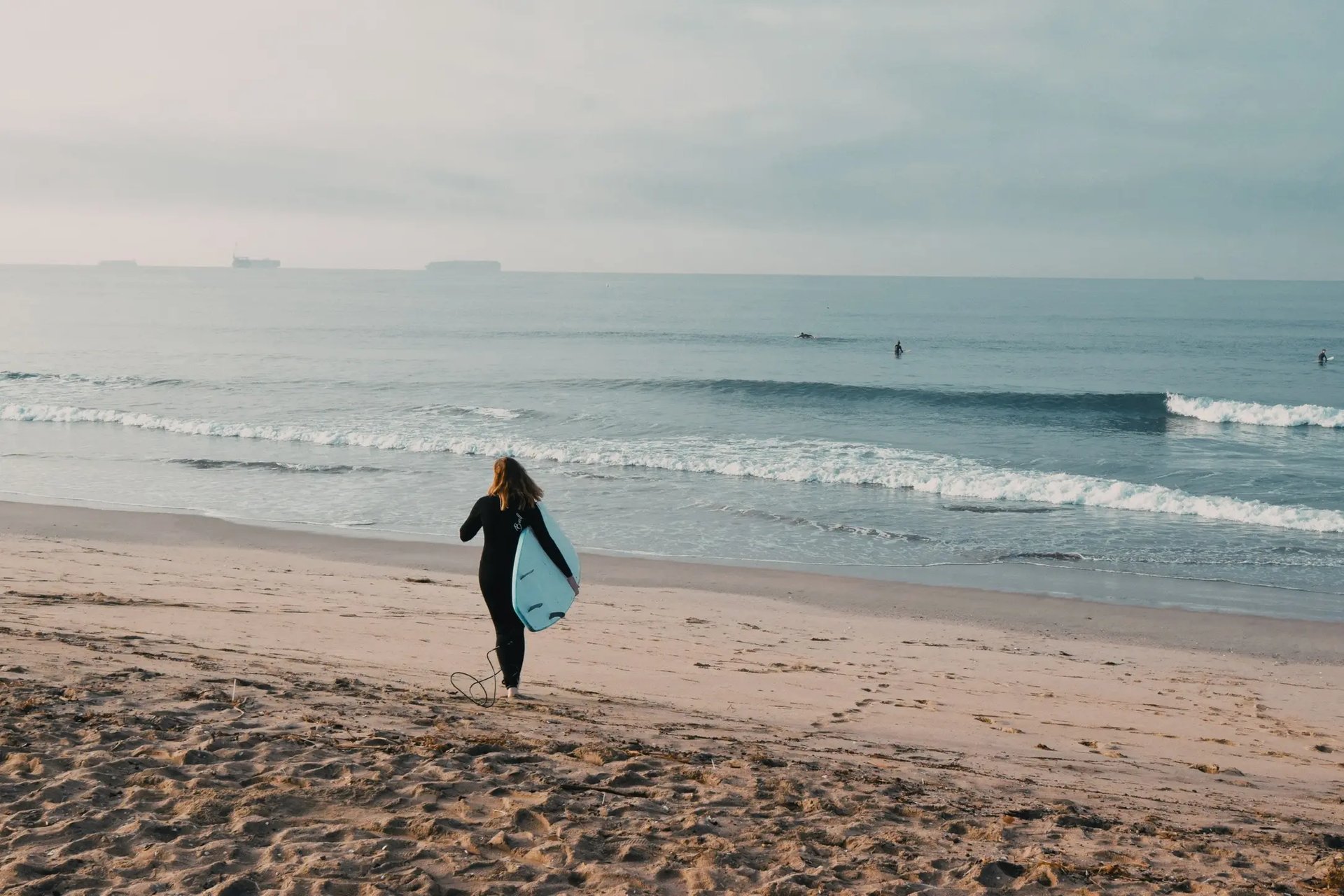 Surferin am Strand von Long Beach, bereit, die Wellen des Pazifischen Ozeans zu genießen.