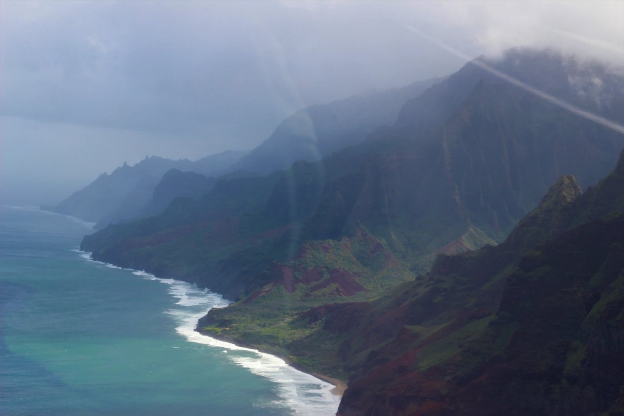 Küstenlinie von Hawaii aus der Vogelperspektive mit Bergen und Meer im Hintergrund.