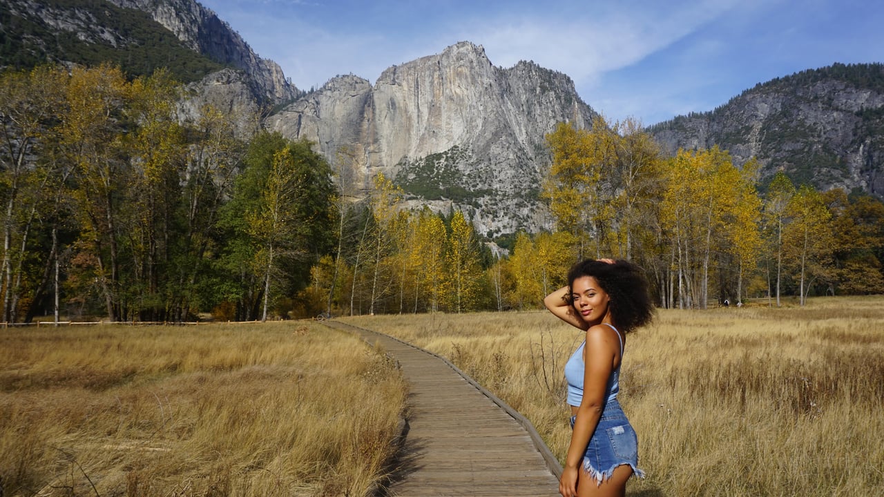 Studentin steht auf einem Holzsteg mit Blick auf die beeindruckenden Felsen im Yosemite Nationalpark, Kalifornien.