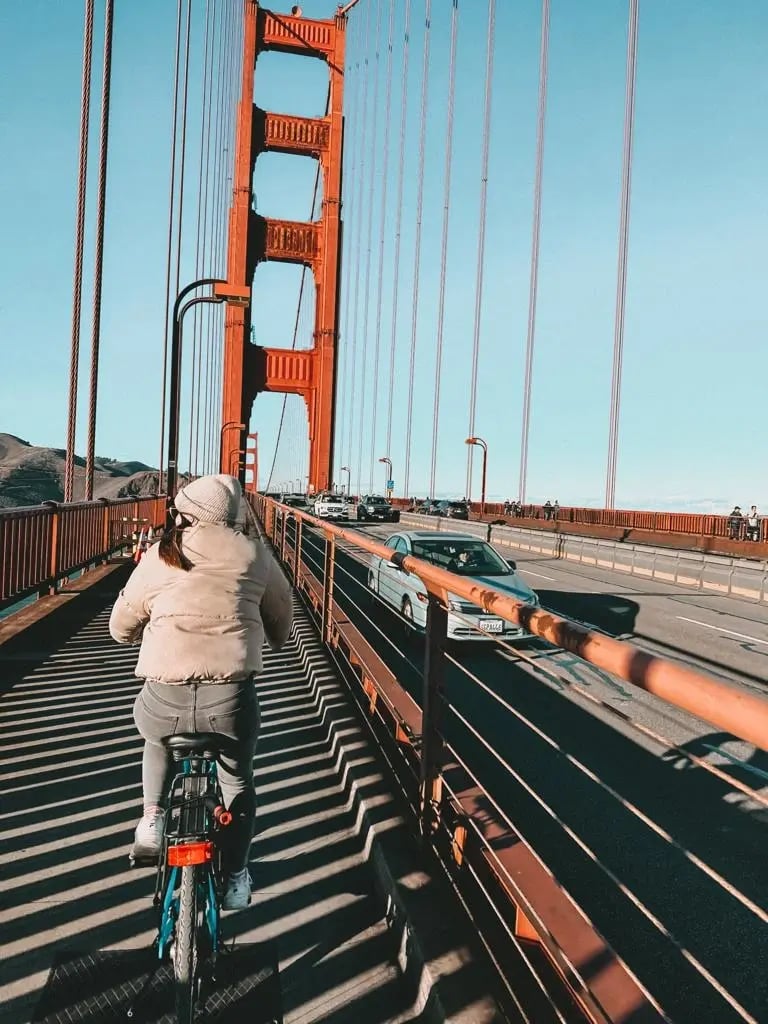 Studentin auf der Golden Gate Bridge mit Blick auf Autos und Brücke in San Francisco.