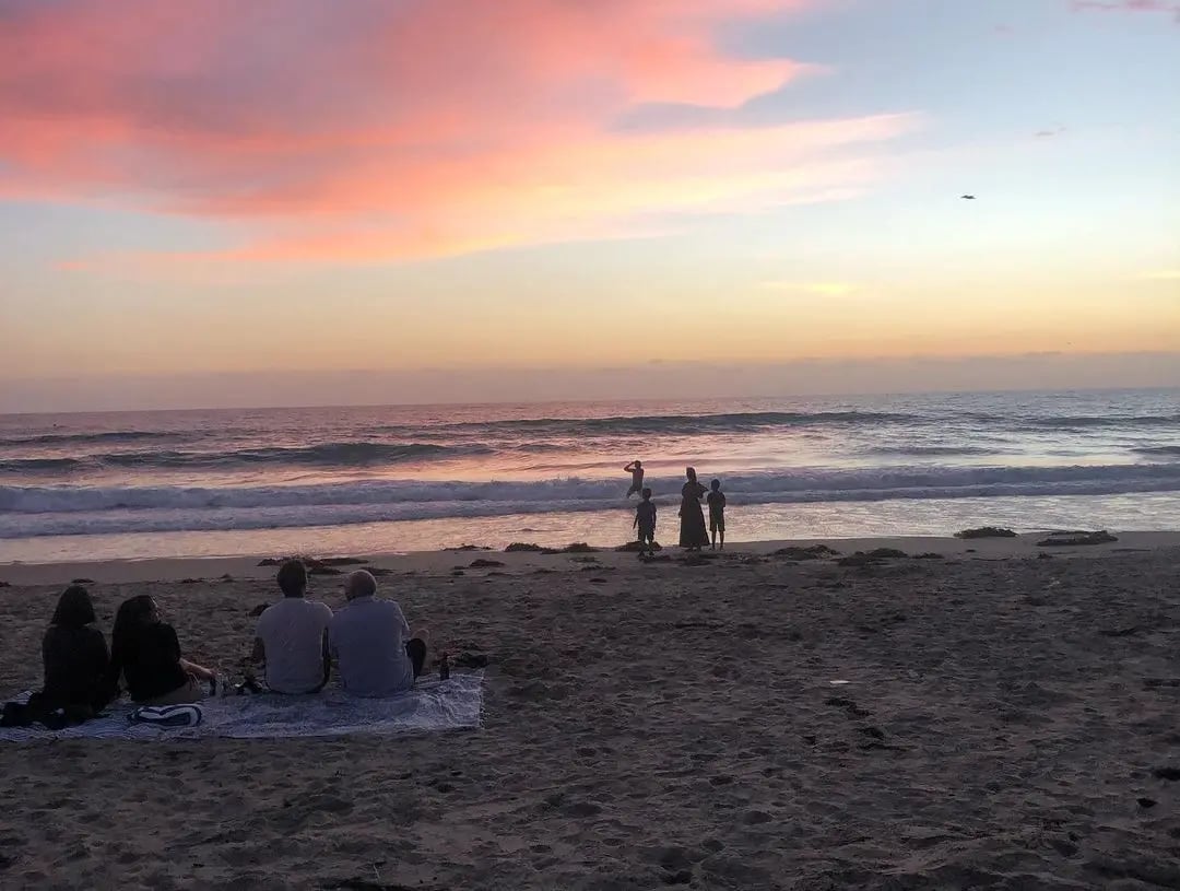 Sonnenuntergang am Strand von San Diego mit Silhouetten von Menschen im Vordergrund.