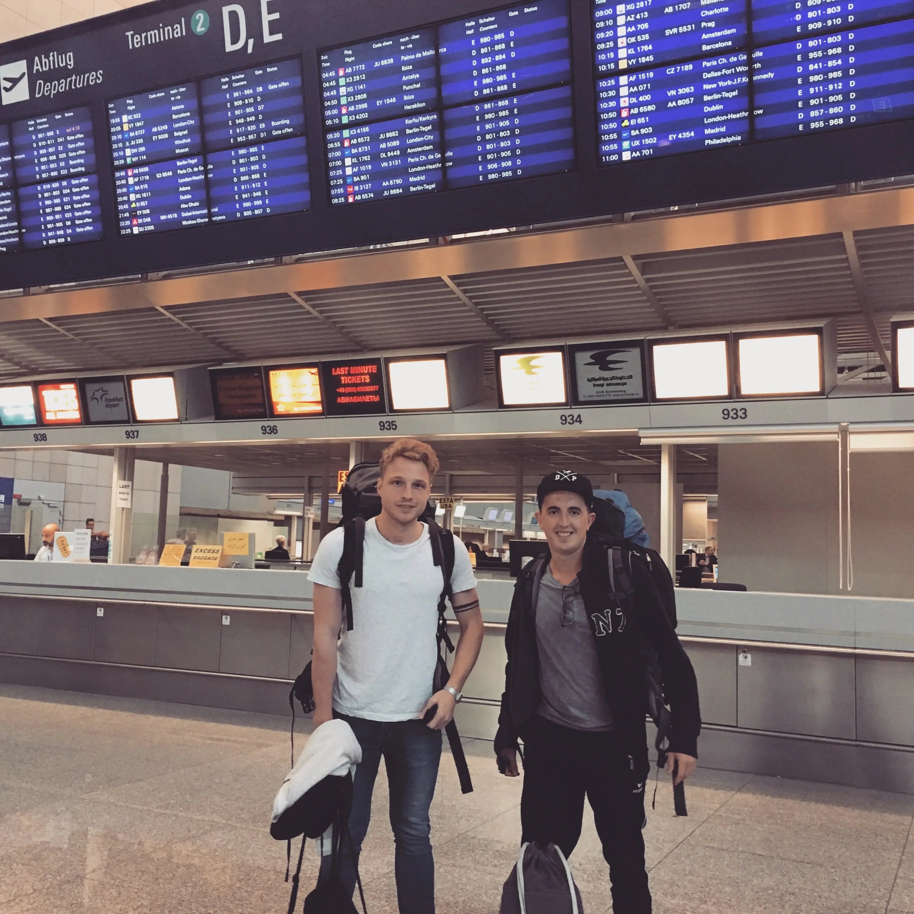 Zwei Studierende mit Rucksäcken am Flughafen, bereit für ein Abenteuer.