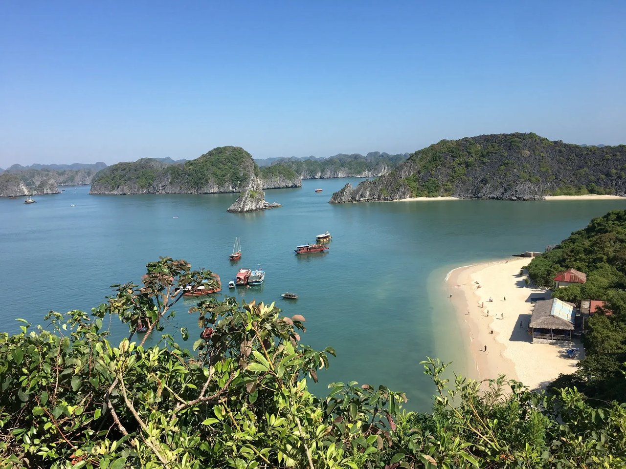 Eine malerische Bucht in Vietnam mit grünen Inseln und traditionell ankernden Booten.