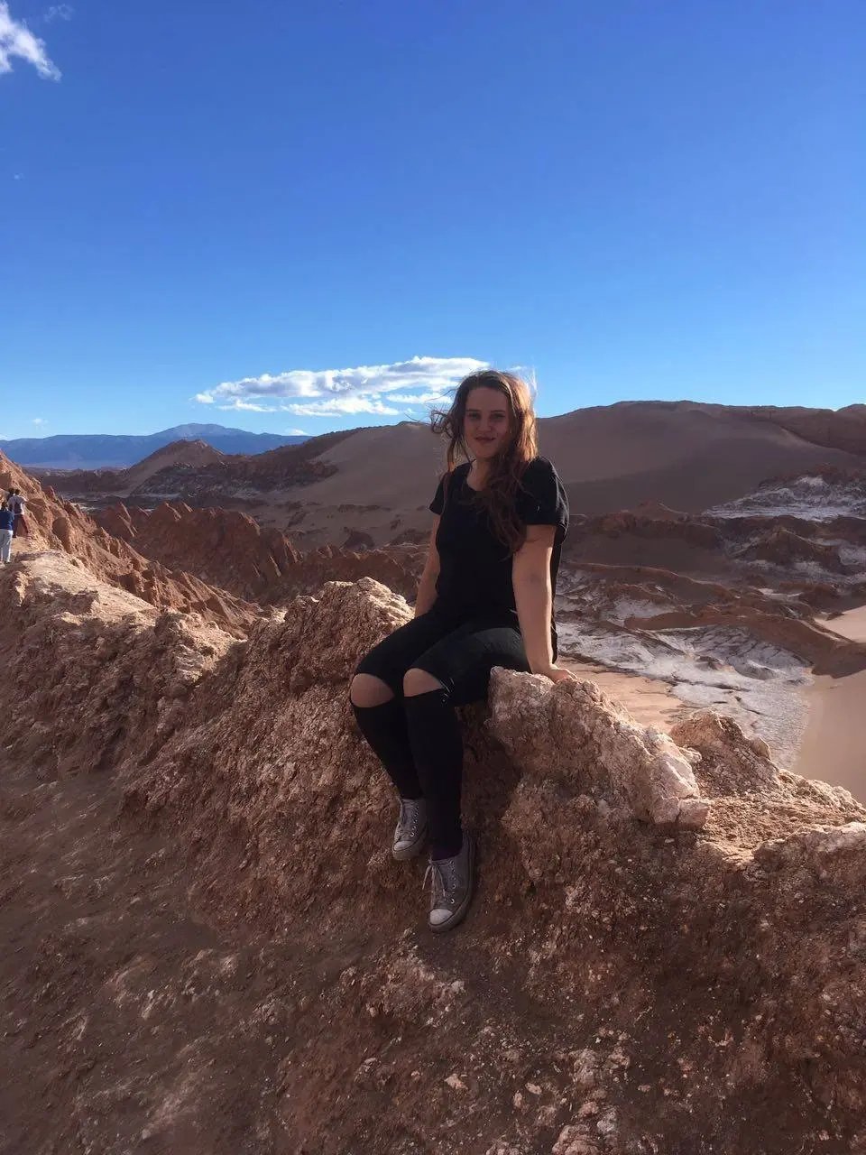 Studentin der Universidad Adolfo Ibanez in Chile sitzt auf einer Felsformation in der Atacama-Wüste und genießt die Aussicht.