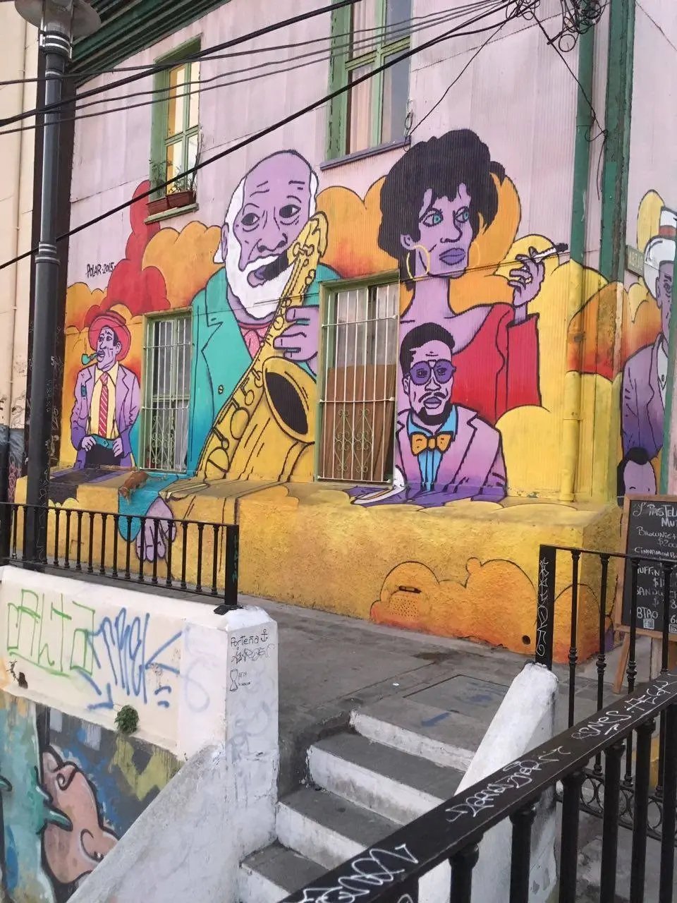 Farbenfrohes Graffiti in Valparaíso, Chile, mit künstlerischen Darstellungen von Musikern und Stadtleben.
