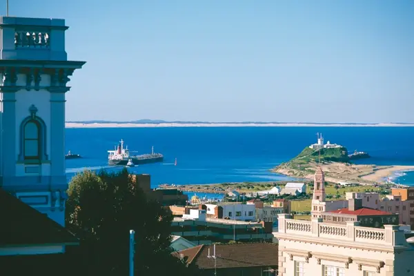 Aussicht auf Newcastle mit blauer Küste, Schiffen und historischer Architektur.